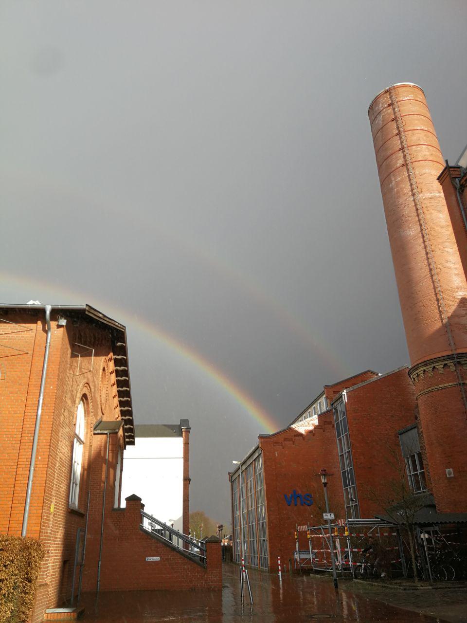 Links in Bild das Stadtmusuem auf der Nordwolle, rechts die VHS, darüber ein Gewitterhimmel mit Regenbogen